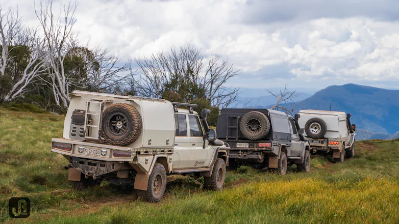 3 modified 4x4 vehicles off roading together over mountains in Australia, all with canopies fitted